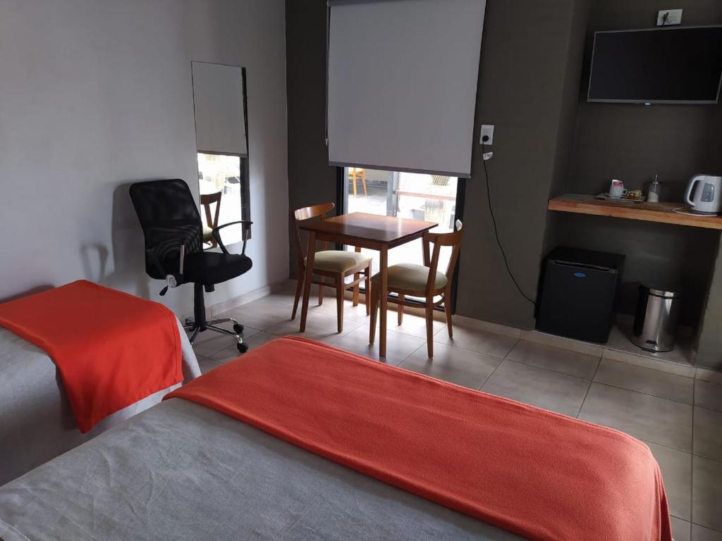 Habitación de hotel con 1 dormitorio con escritorio y mesa en Lantonia en Oncativo