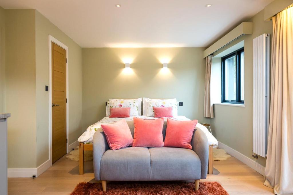 a bedroom with a bed with pink pillows at South Downs Studio - bijou hikers hideaway in Old Town