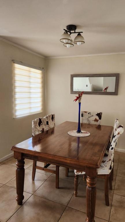 una mesa de comedor con 2 sillas y un jarrón. en Casa Nueva en Condominio Tranquilo en Osorno