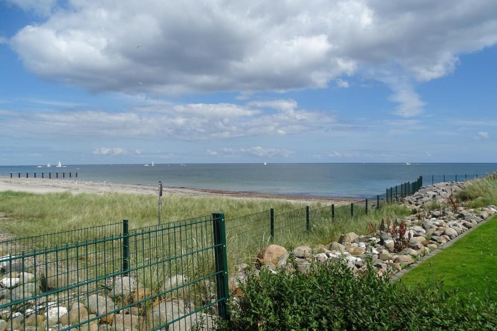 a fence next to a beach with the ocean at Strandkrabbe in Olpenitz