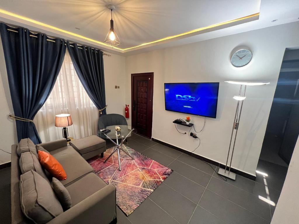 a living room with a couch and a tv at Karjel Homes Apartments in Sunyani