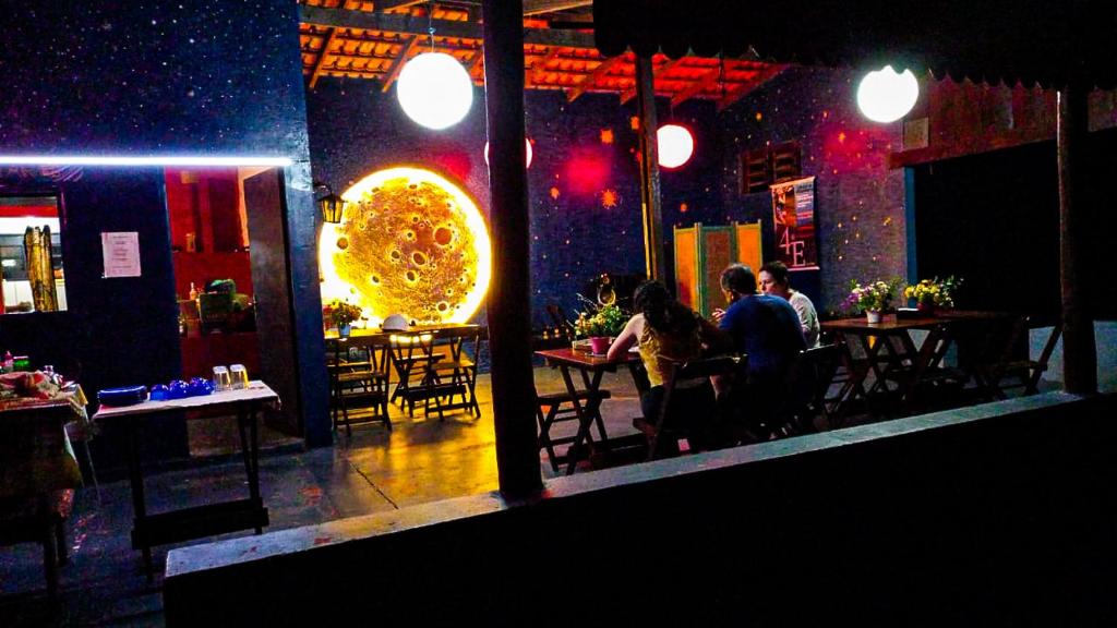 um grupo de pessoas sentadas em mesas em um restaurante em Pousada Estação Lunar em São Domingos