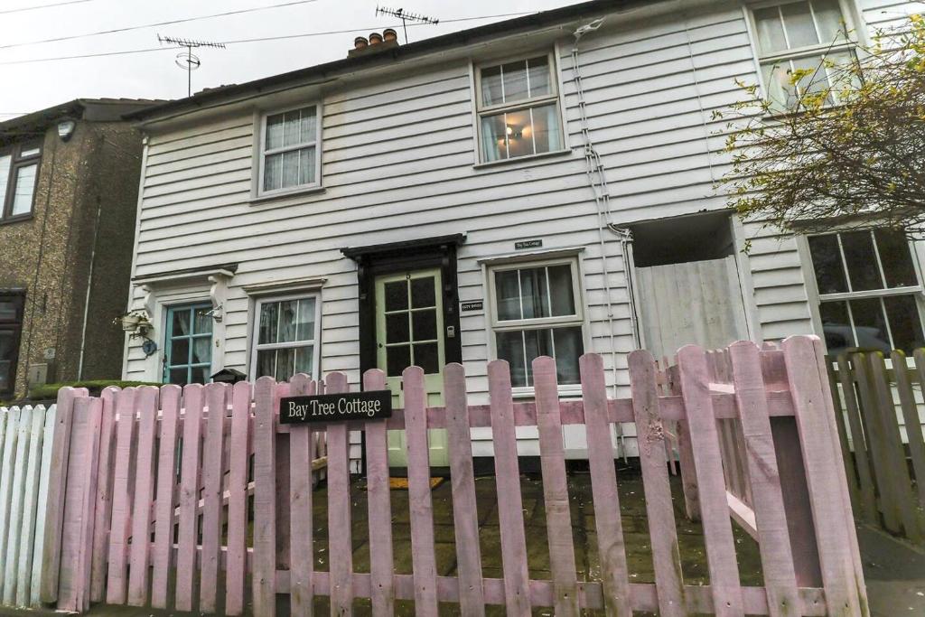 a pink fence in front of a white house at Beautiful 3-Bed Cottage in Burnham-on-Crouch in Burnham-on-Crouch