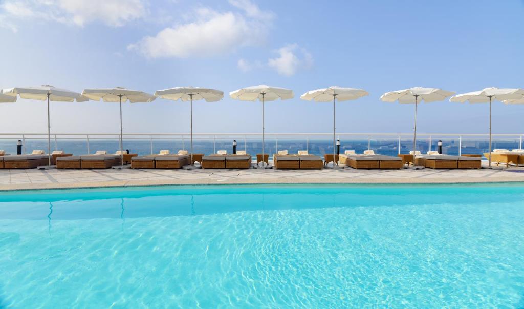 a swimming pool with chairs and umbrellas on a building at XQ El Palacete in Morro del Jable