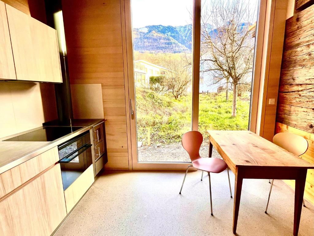 une cuisine avec une table et une grande fenêtre dans l'établissement Gädeli, à Sachseln