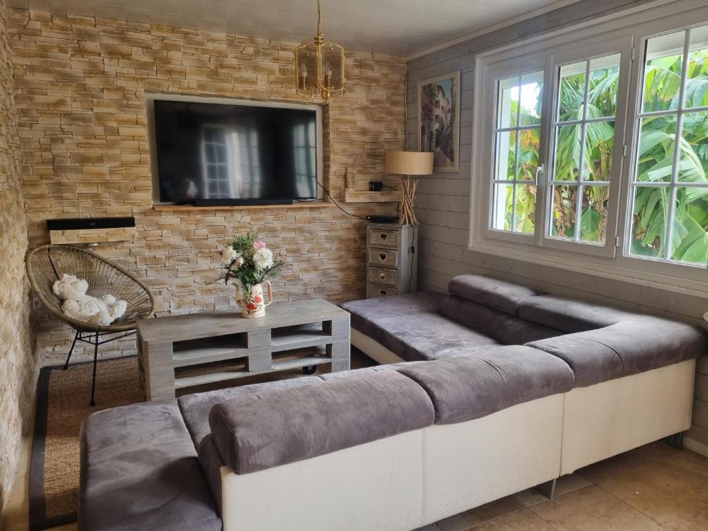 sala de estar con sofá y TV en A la maison du bonheur, en Neuilly-sous-Clermont