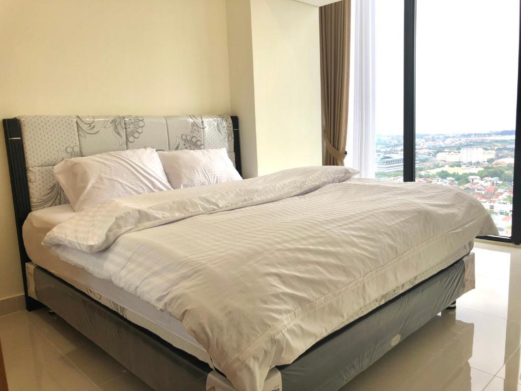 een bed in een slaapkamer met een groot raam bij Sea View One Bedroom Apartment In Bluhen Tower in Batam Center
