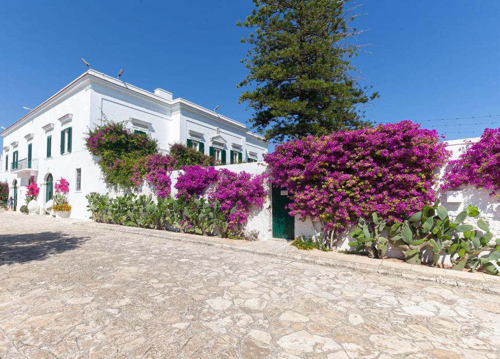 ein weißes Gebäude mit lila Blumen darauf in der Unterkunft La Masseria by Masseria San Nicola Savelletri in Savelletri di Fasano