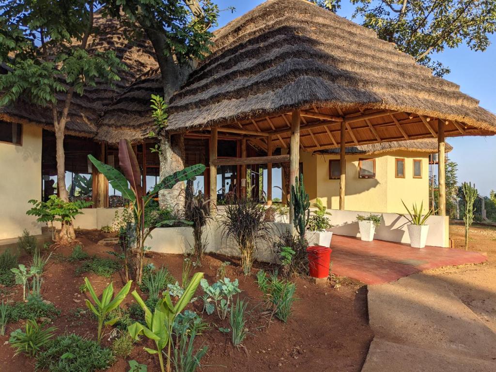 a house with a thatched roof and a porch at Cwmbale Eco-Safari Lodges, Restaurant and Zoo. in Mbale