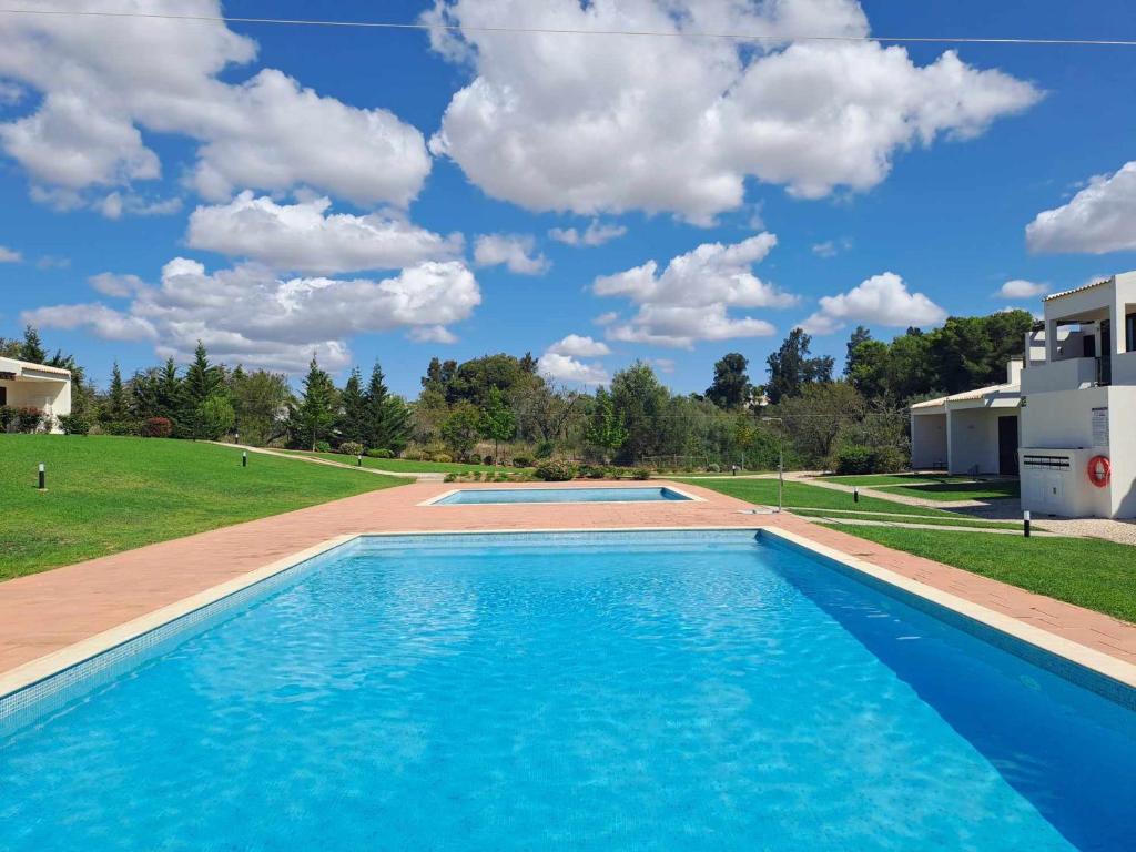 a swimming pool with a blue sky with clouds at Comfort relax w pool near beach in Alvor