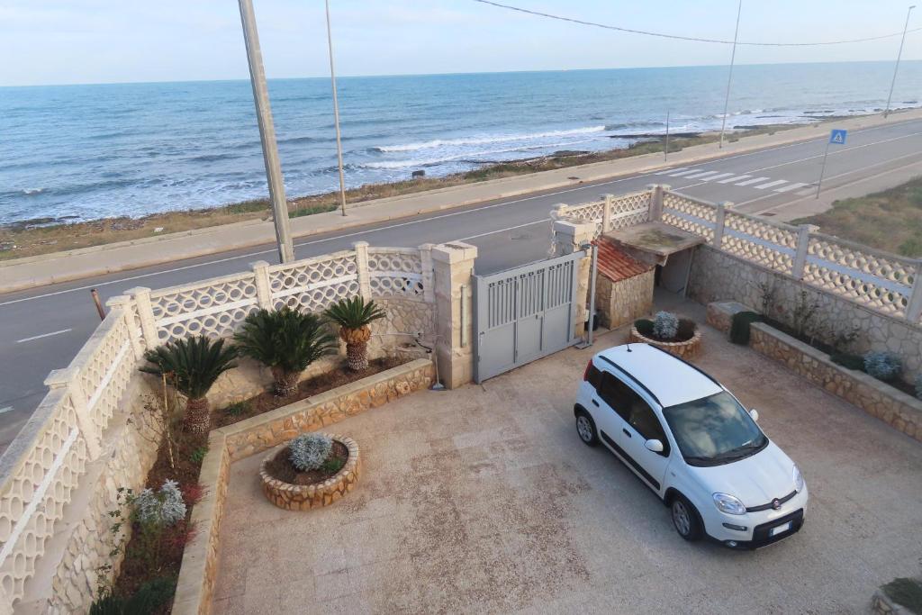 ein weißes Auto, das auf einem Balkon neben dem Meer parkt in der Unterkunft California in Bari