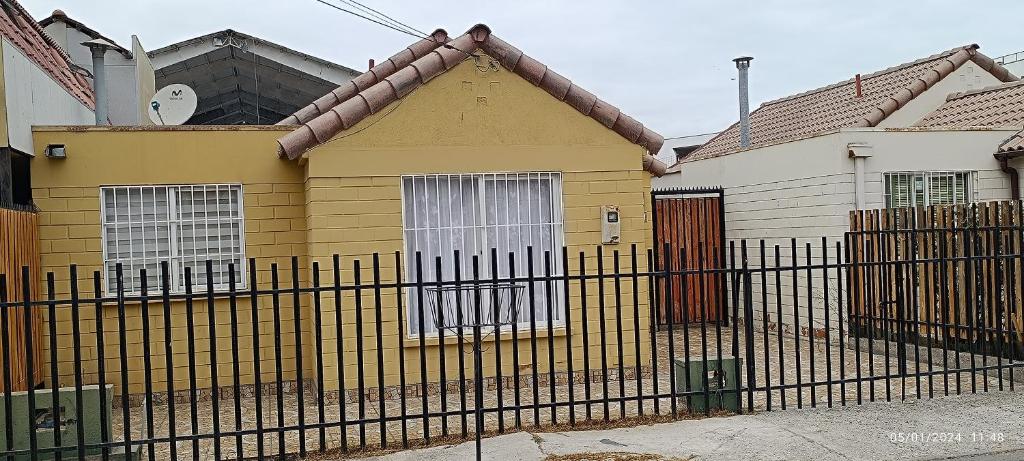 a yellow house with a fence in front of it at Casa en la serena in La Serena