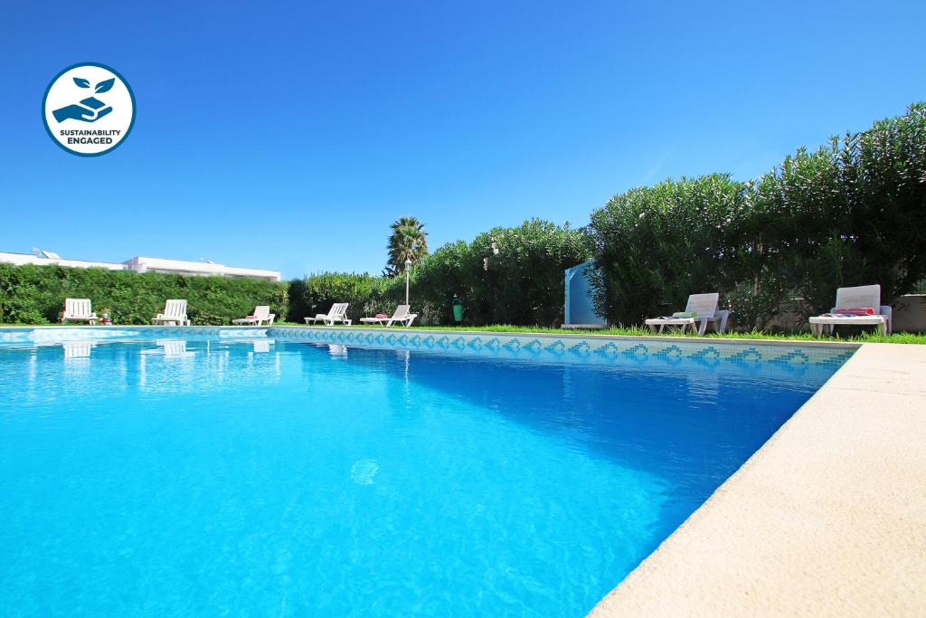 una gran piscina azul con sillas y árboles en Townhouse Palm Beach by Algarve Vacation, en Albufeira