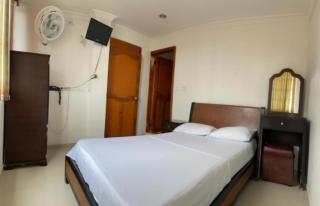Hotel Sangil Tuluá في تولوا: غرفة نوم بسرير ونافذة ومروحة