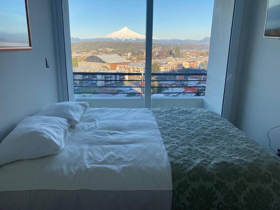 a bed in a room with a large window at Departamento nuevo en Villarrica in Villarrica