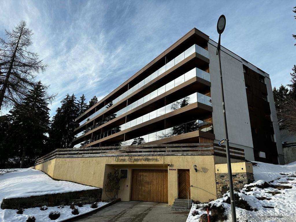 un gran edificio con garaje en la nieve en Renovated Mountain View Apartment - Les Eperviers, en Crans-Montana