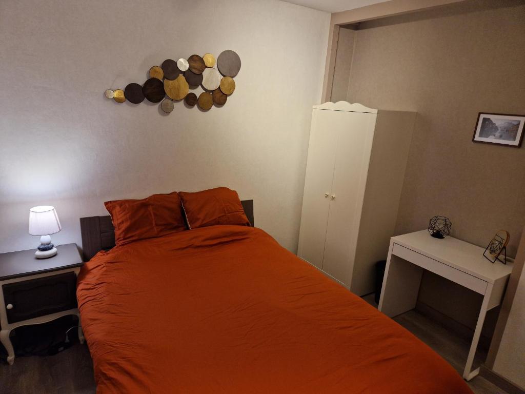 - une chambre avec un lit doté d'un couvre-lit orange dans l'établissement Chambre au calme à Ramillies - chez Ben, à Ramillies