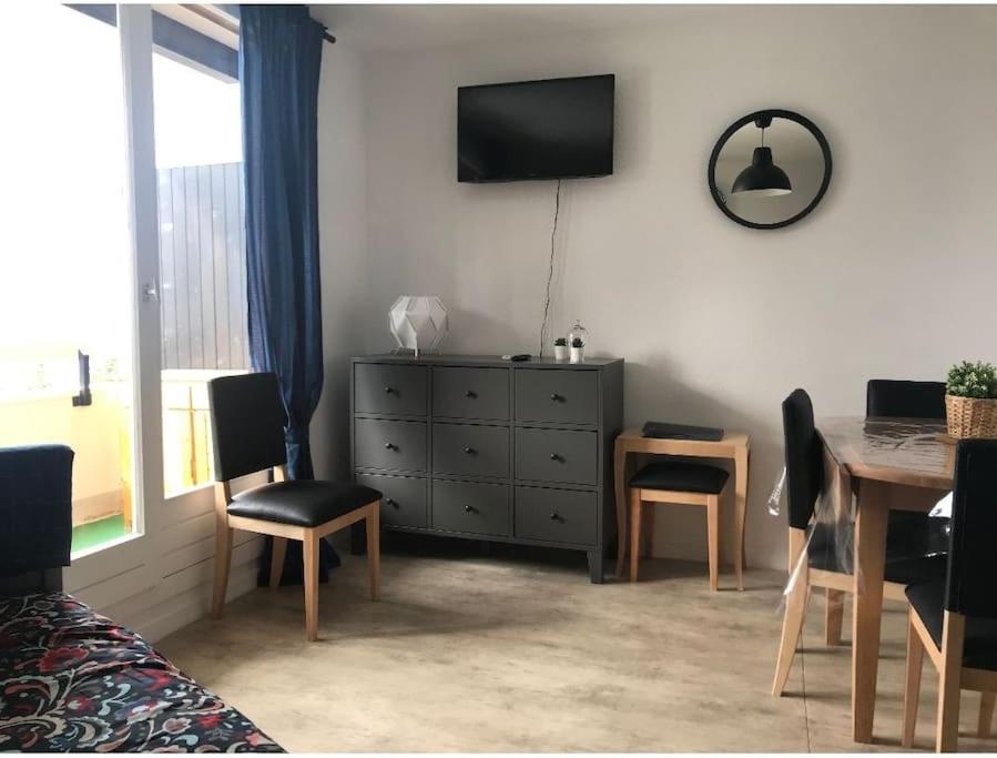 uma sala de estar com uma mesa e uma cómoda com uma televisão em Appartement 6 couchages aux pieds des pistes em Chamrousse