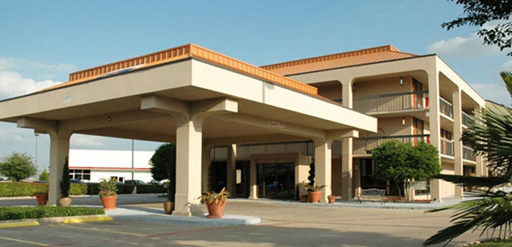 a large building with a porch in a parking lot at Executive Inn in Dallas