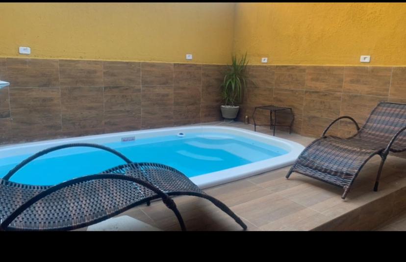 uma piscina com duas cadeiras e uma banheira em Casa praia Serrambi em Porto de Galinhas