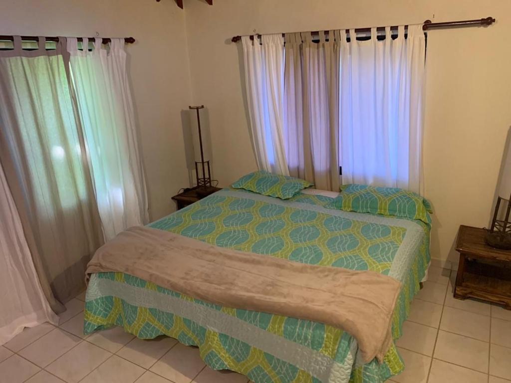 a bedroom with a bed in a room with windows at Villa Fe Esperanza - Vistas al Valle de Constanza in Constanza