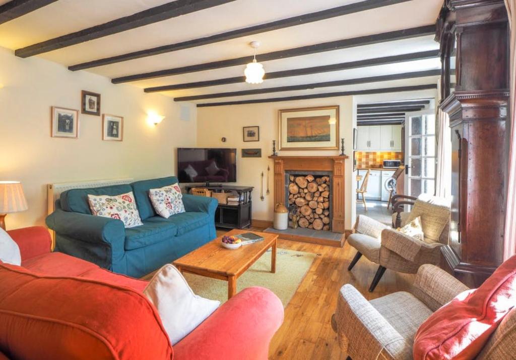 un soggiorno con divano blu e tavolo di Pontfair - Charming Cottage 10 mins walk from beach a Llangrannog