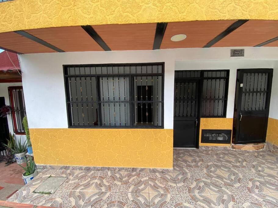 un bâtiment jaune et blanc avec trois portes noires dans l'établissement Apartamento familiar o personal, à Ibagué
