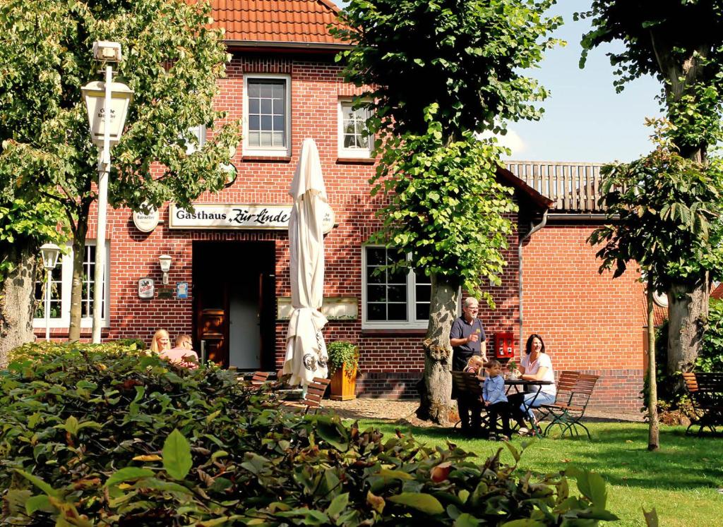 eine Gruppe von Menschen, die vor einem Backsteingebäude sitzen in der Unterkunft Hotel Zur Linde in Neddenaverbergen