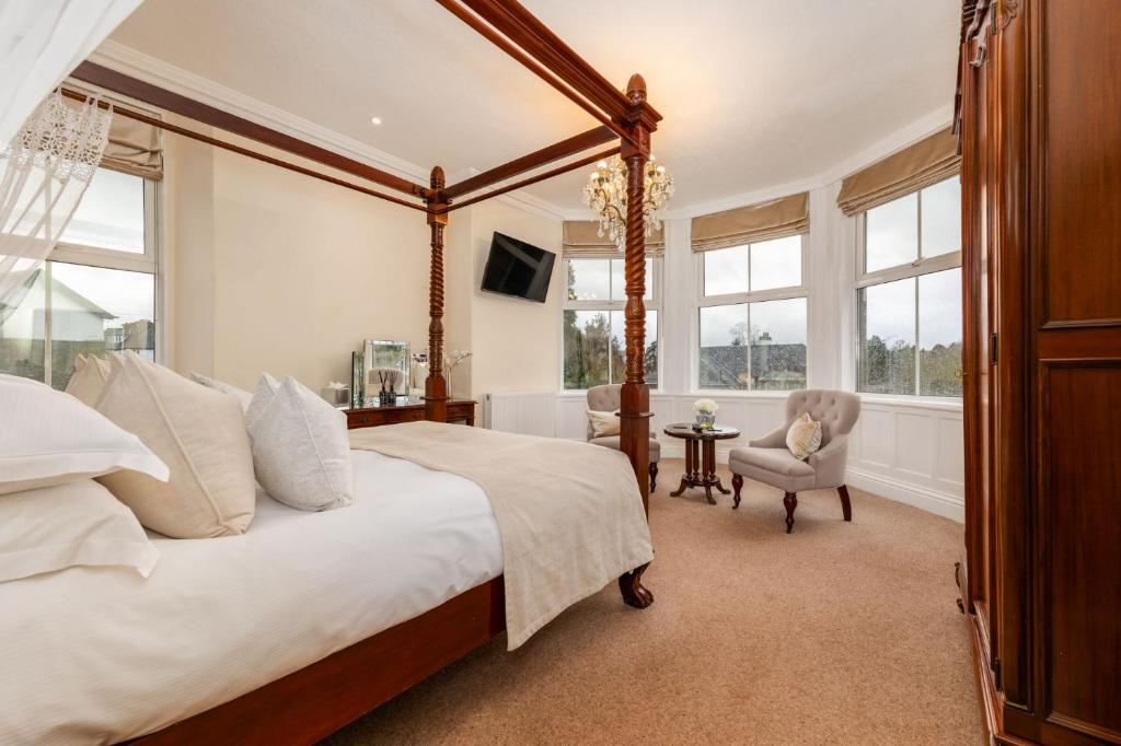 a bedroom with a canopy bed and a chair at Wheatlands Lodge Guesthouse - Adults Only - Free car park - Licensed Venue in Windermere