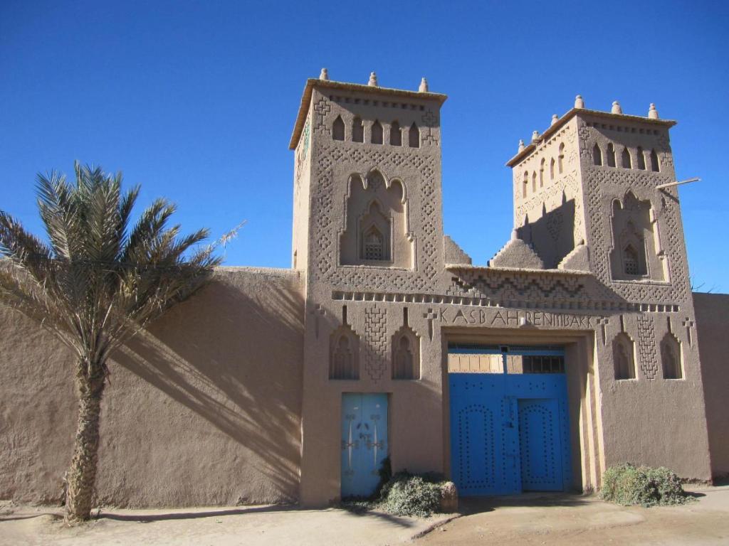 ein Gebäude mit einer blauen Tür und einer Palme in der Unterkunft Gite Kasbah La Palmeraie in Skoura