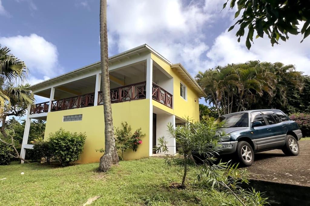 une voiture garée devant une maison jaune dans l'établissement LaCaye - Home in Creole, à Calibishie