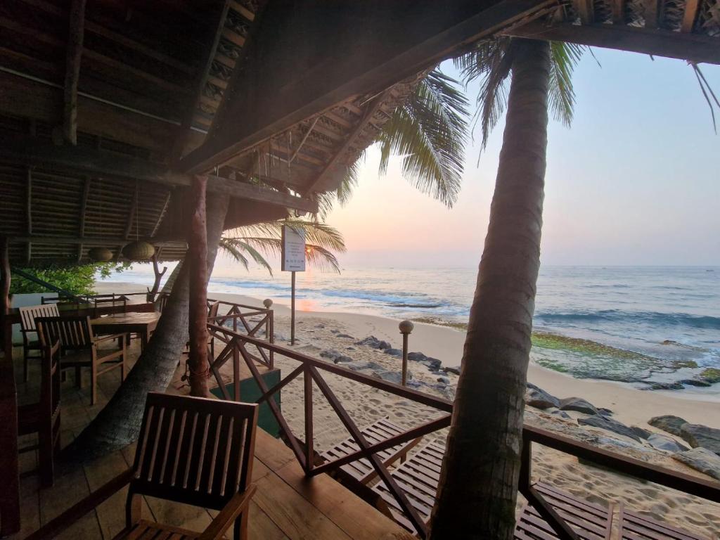 a view of the beach from the porch of a restaurant at Panorama Beach Hotel in Tangalle