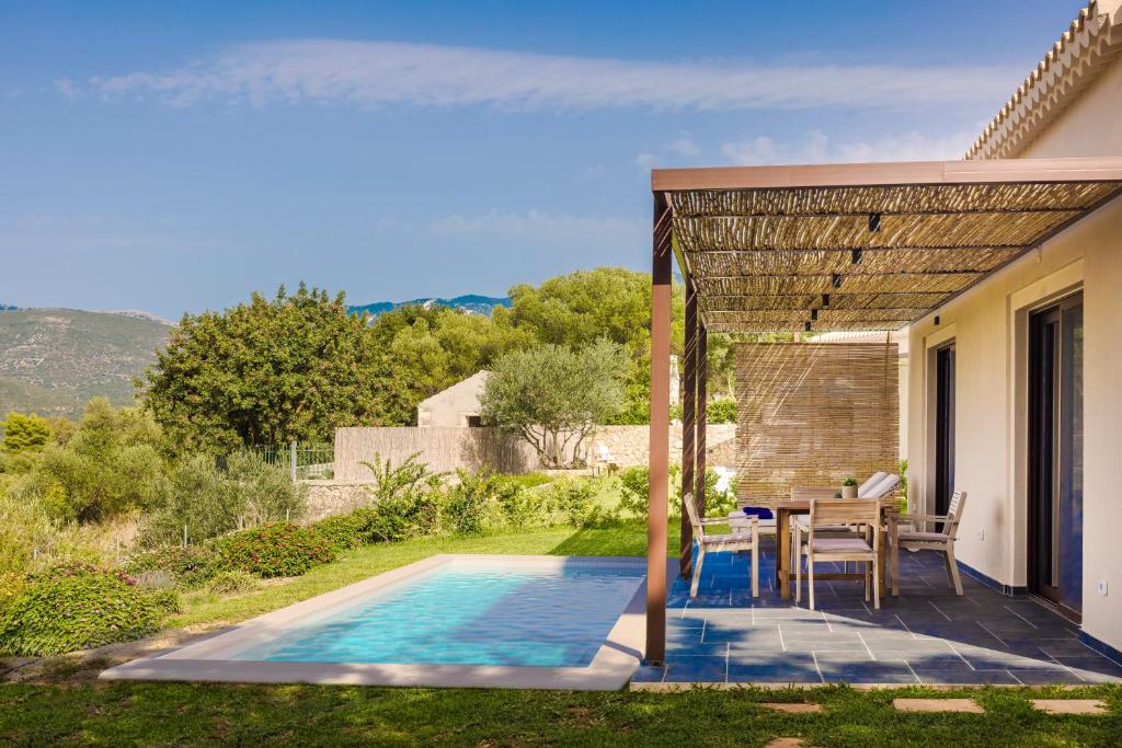 un patio con mesa y sillas junto a una piscina en FRG Villas - Villa Cantare en Kefallonia
