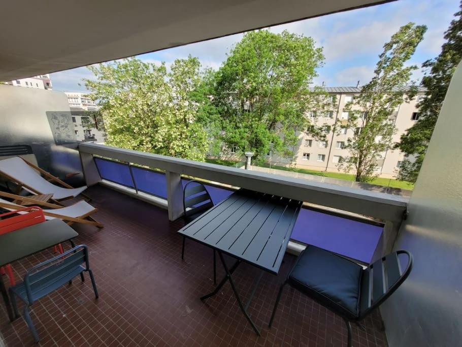 einen Balkon mit einem Tisch und Stühlen sowie einem großen Fenster in der Unterkunft Superbe appartement, terrasse, accès direct RER in Massy
