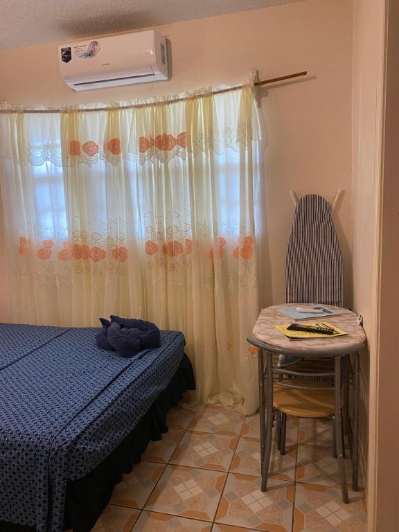 a bedroom with a bed and a table with a chair at Beverley's Guest House, Nevis in Nevis