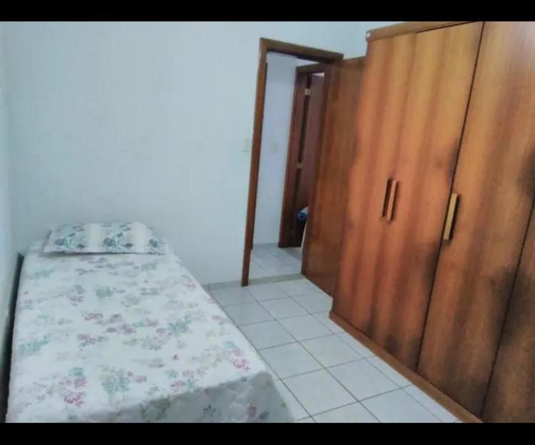 a bedroom with a bed and wooden cabinets at Quarto solteiro Praia de Camburi in Vitória