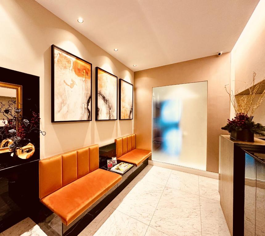 ein Wartezimmer mit orangefarbenen Stühlen und Gemälden an der Wand in der Unterkunft Babuino Palace&Suites in Rom
