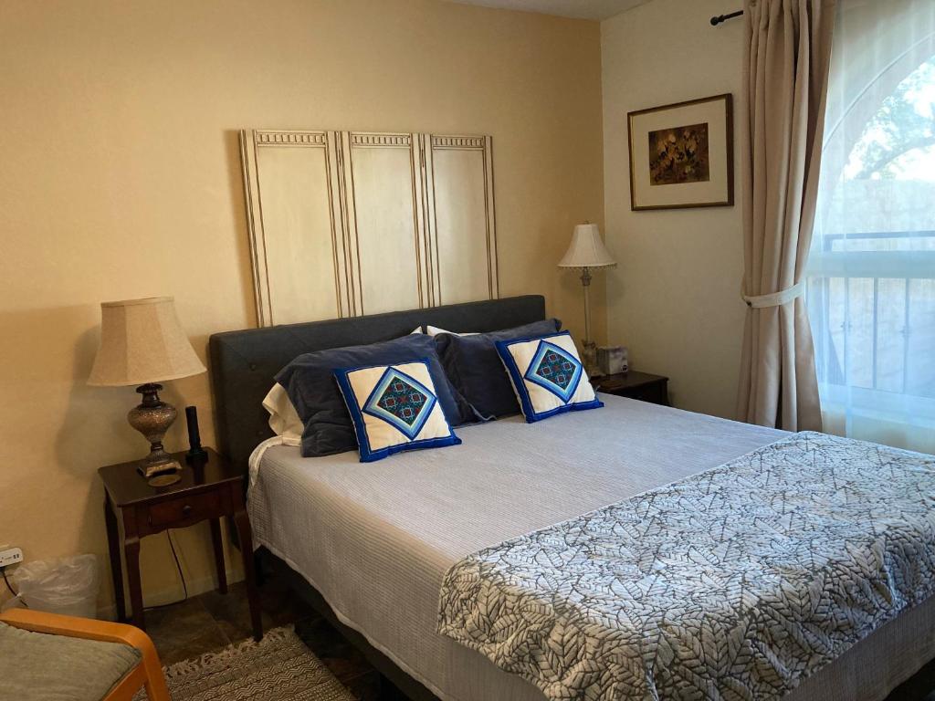 a bedroom with a bed with blue pillows and a window at Desert retreat close to downtown/ U of A, 1-10 in Tucson
