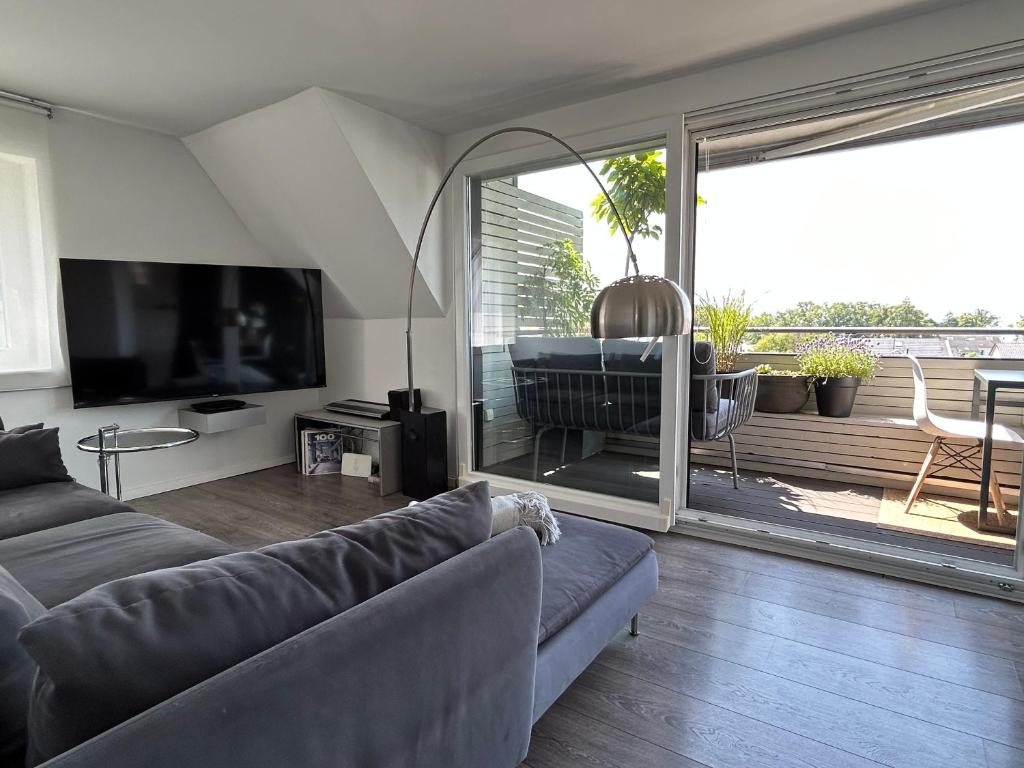 ein Wohnzimmer mit einem Sofa und einem TV in der Unterkunft Rooftop Living inkl Homeoffice bis 4 Personen in Friedrichshafen