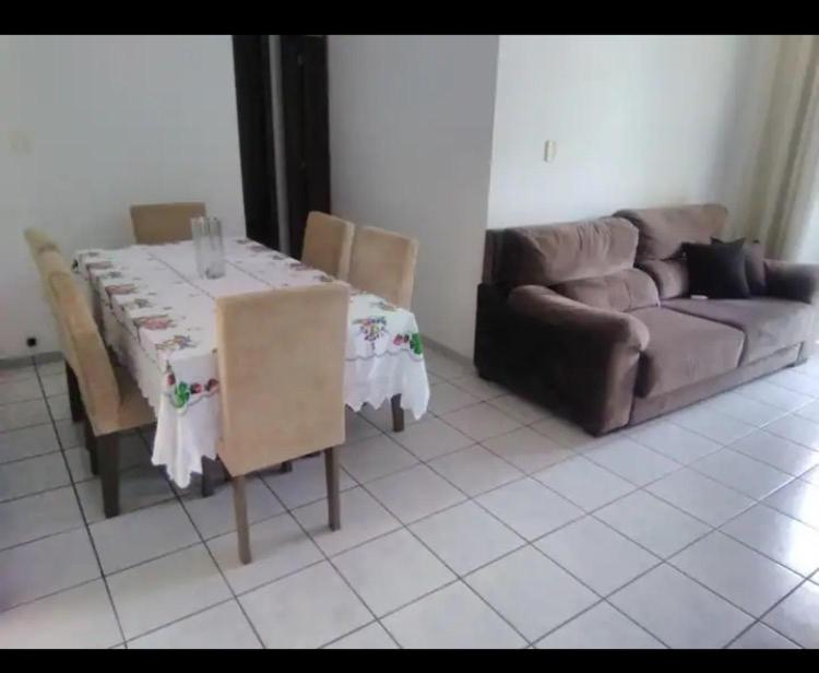 ein Wohnzimmer mit einem Tisch und einem Sofa in der Unterkunft Suíte Praia de Camburi in Vitória