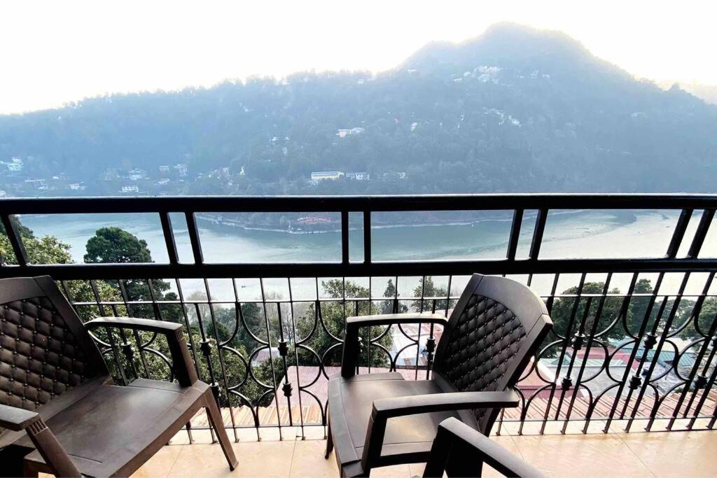balcón con 2 sillas y vistas a la montaña en The Wooden Lodge en Nainital