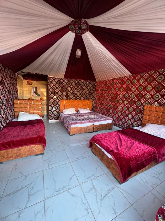 a room with three beds in a tent at Wadi rum Golden land camp in Wadi Rum