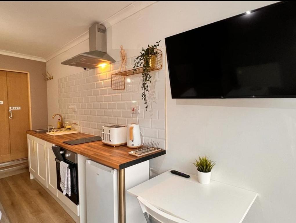 a kitchen with a counter and a tv on the wall at Cosy & Convenient space near M1, EM Airport & City in Nottingham