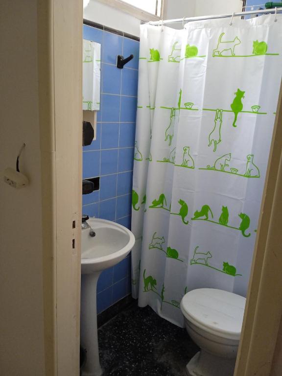 a bathroom with a toilet a sink and a shower curtain at La Perla alojamiento in Mar del Plata