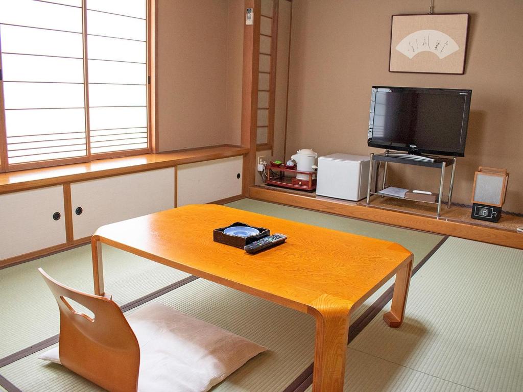 uma sala de estar com uma mesa de madeira e uma televisão em Hotel Akaboshitei - Vacation STAY 57417v em Echizen