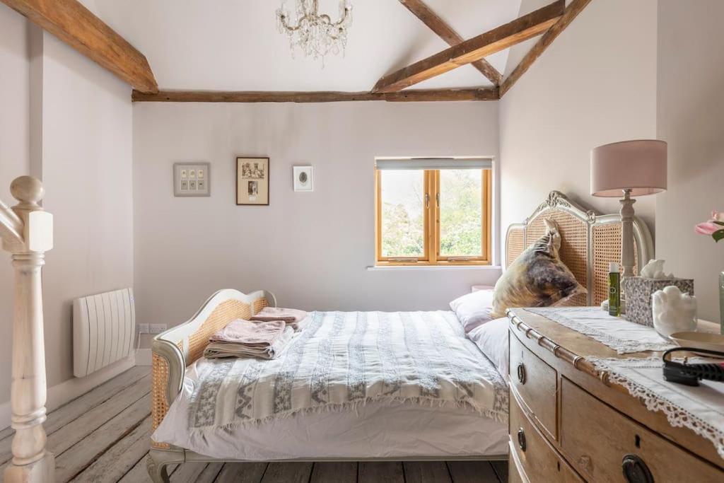 a bedroom with a bed with a dresser and a window at Luxury Apartment, The Barn, Cookham in Cookham