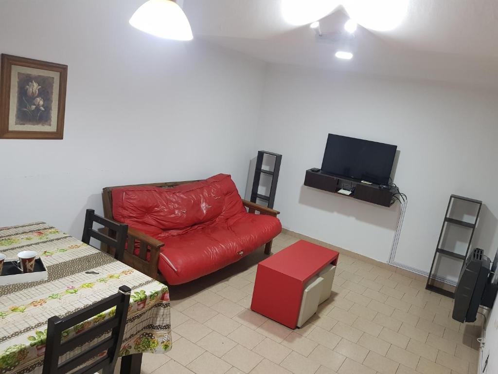 salon z czerwoną kanapą i telewizorem z płaskim ekranem w obiekcie La esquina - Alquiler temporario w mieście Santa Rosa
