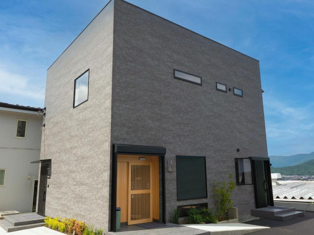 a gray brick house with a wooden door at SWEET VILLA TAKASAMA2 - Vacation STAY 31510v in Fujiyoshida