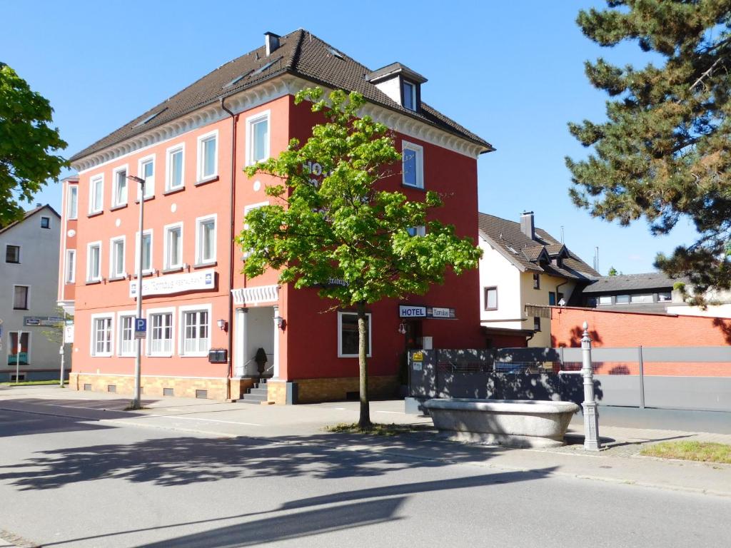 un edificio rojo con un árbol delante de él en Hotel Romäus en Villingen-Schwenningen