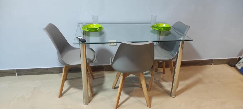 una mesa de cristal con tres sillas y dos tazones verdes. en Suite Jonca en Machala